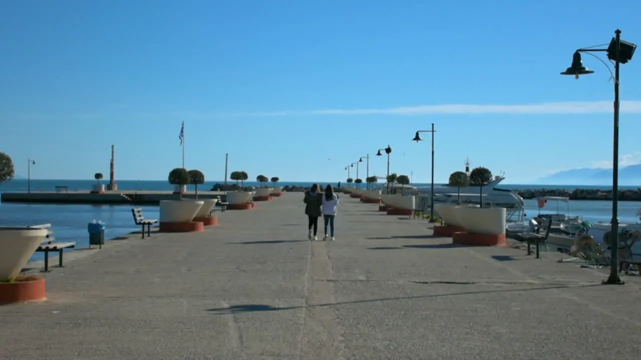 Two girls walking in the sea port at a small city near Athens Greece