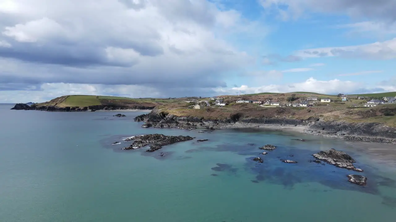 An aerial footage flying backwards over green blue waters of calm sunny Atlantic rugged coastal line and dramatic sky in Ireland