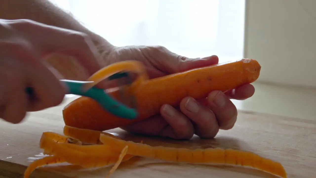 A close up of peeling a carrot with a peeler