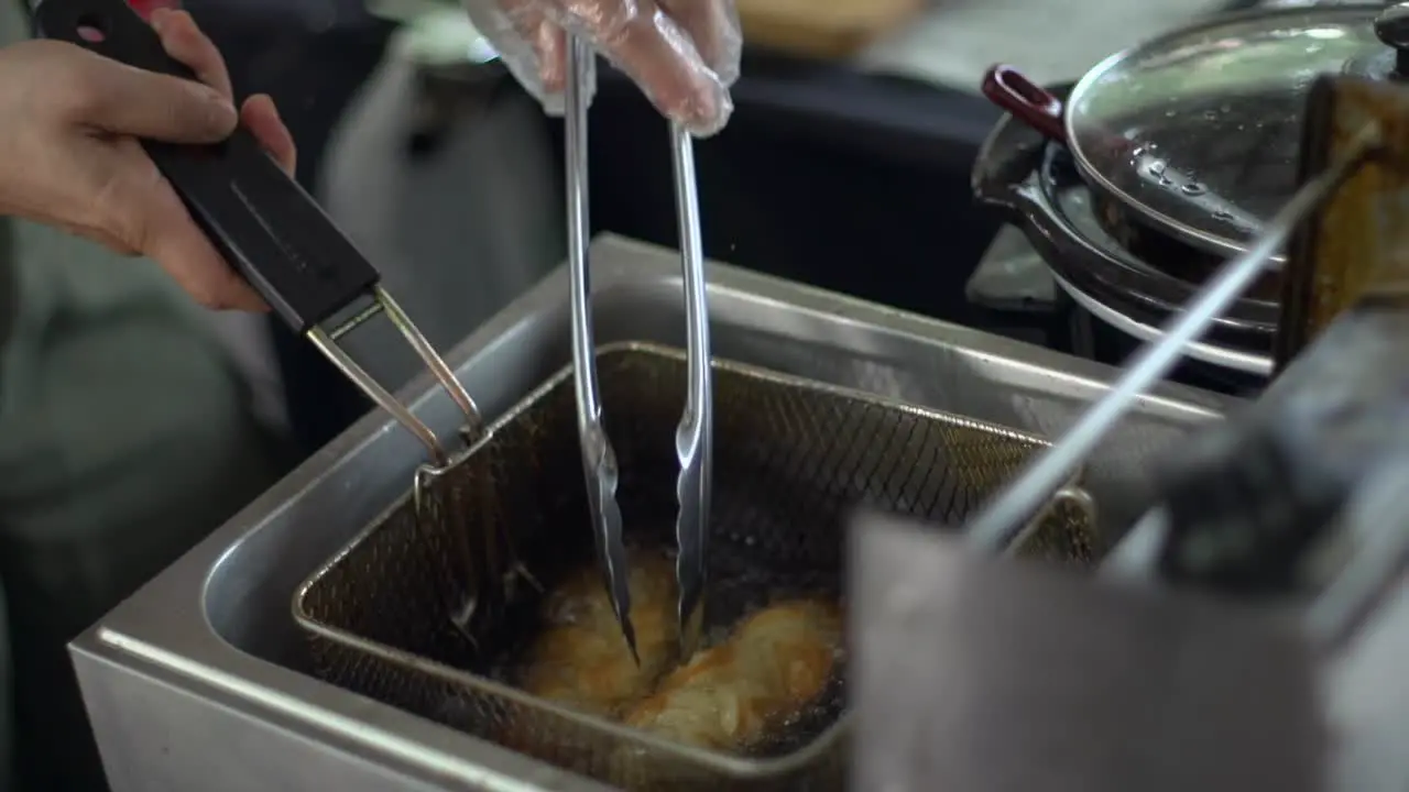 Bread rolls deep fried in vat of boiling hot oil filmed as close up shot in handheld slow motion style