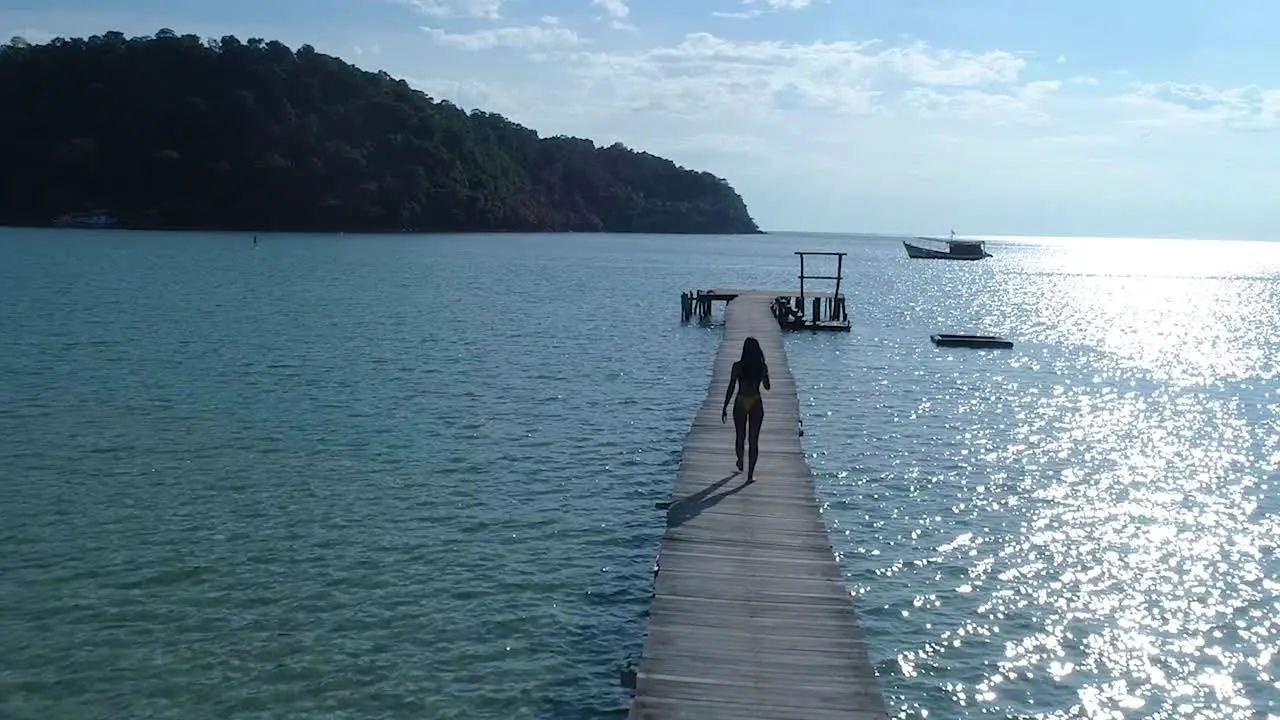 Female walking alone on a pier in the ocean on a tropical island koh kood Thailand