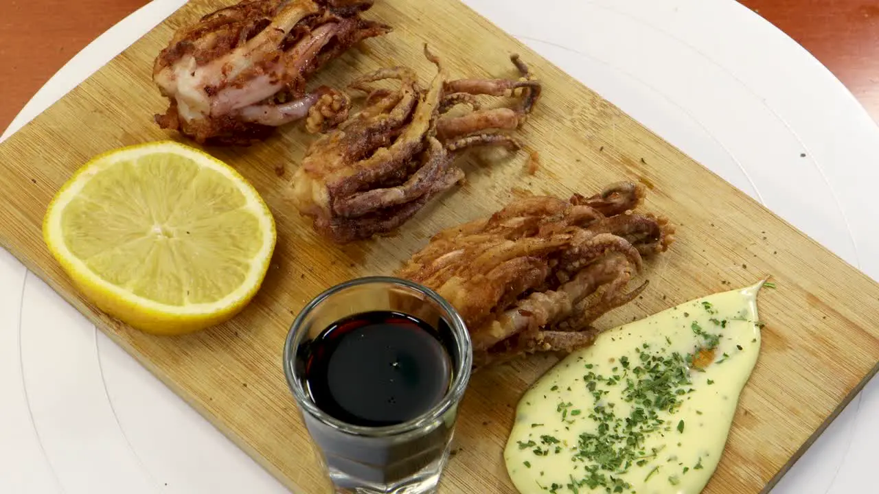 Adding pepper to a wood table with fried squid soy sauce lemon and aioli