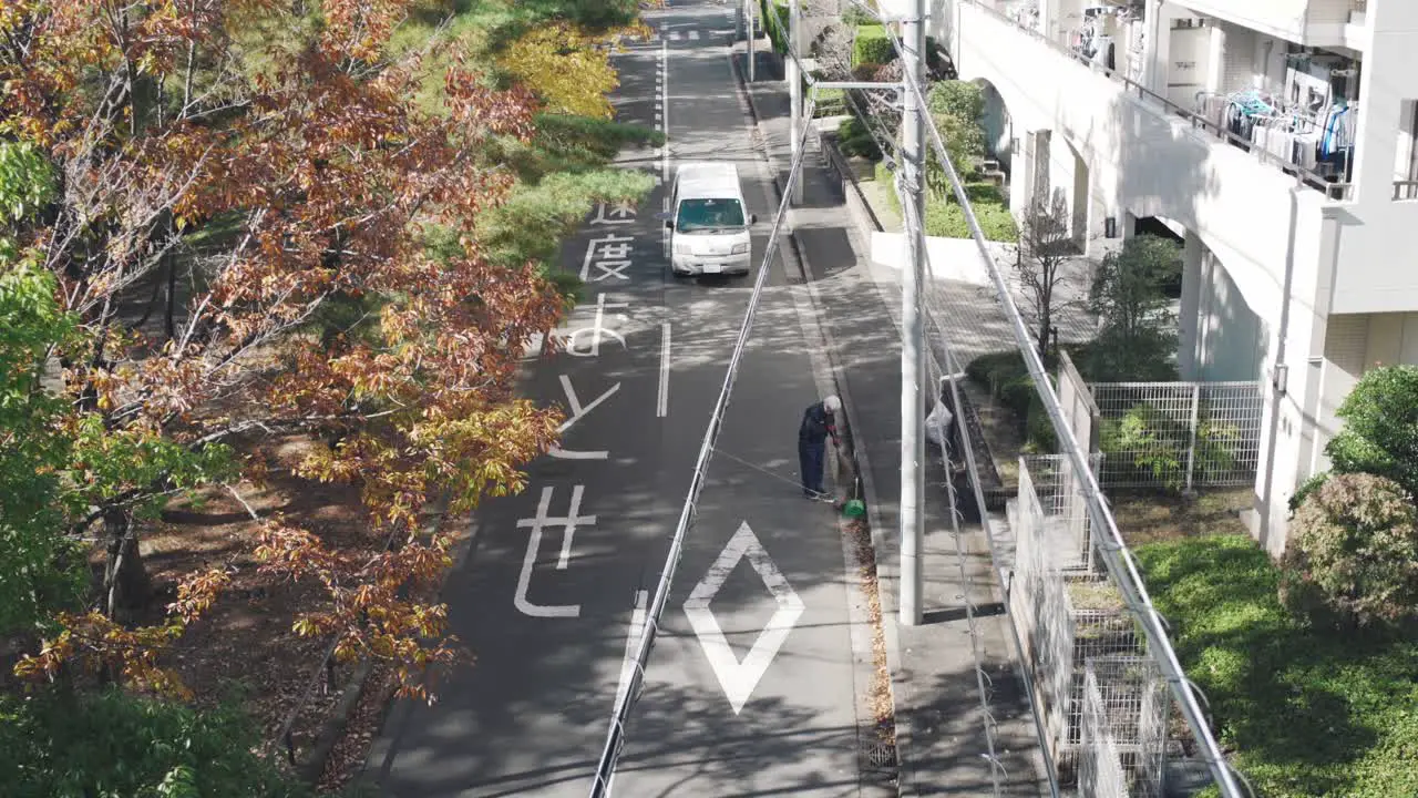 Beautiful Street Of Japan During Fall Season With Red Leaves A Man Sweeping The Fallen Leaves Alongside The Road of Tokyo Japan