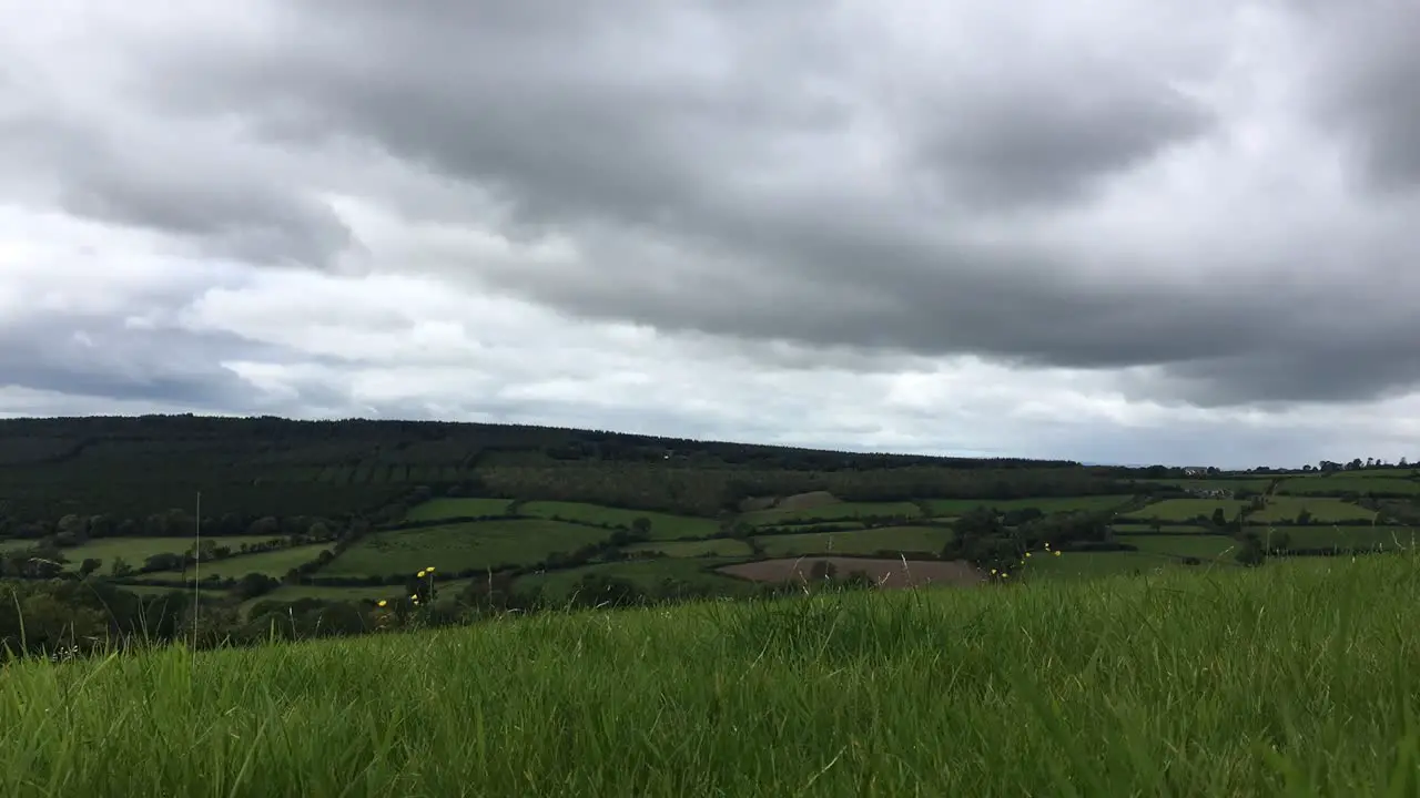 A low down timelapse of dark clouds rolling over beautiful green fields