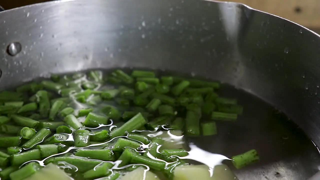 Close up of Potato and Green bean pieces put in pot with water