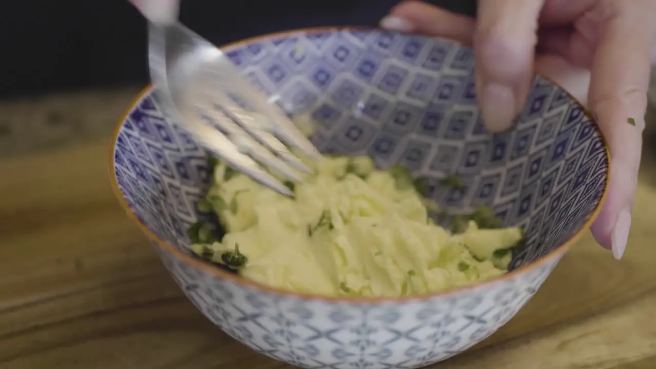 Closeup of a chef making garlic herb butter in a bowl