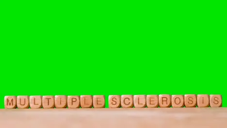 Medical Concept With Wooden Letter Cubes Or Dice Spelling Multiple Sclerosis Against Green Screen Background