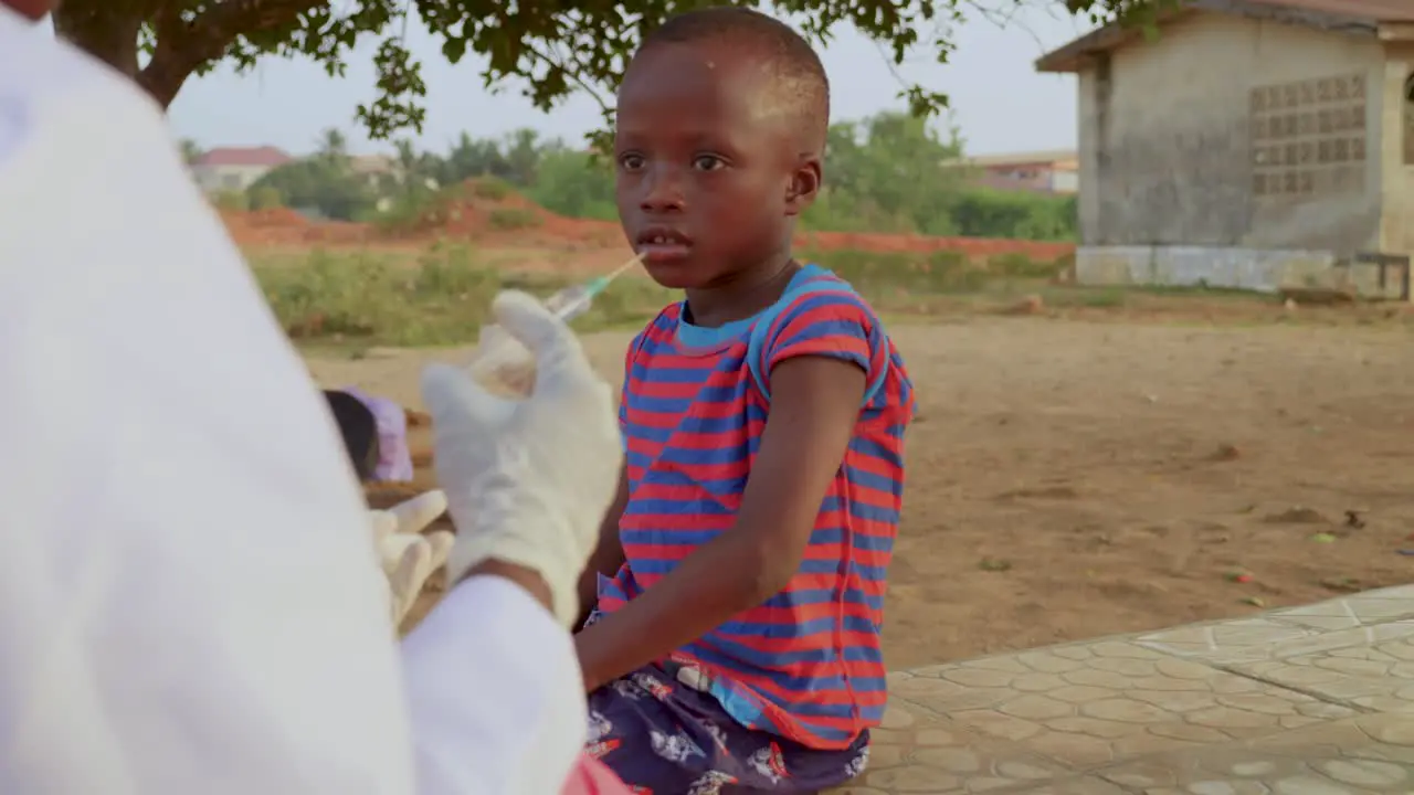 Young child getting booster dose in the left arm from a health care professional in a white coat