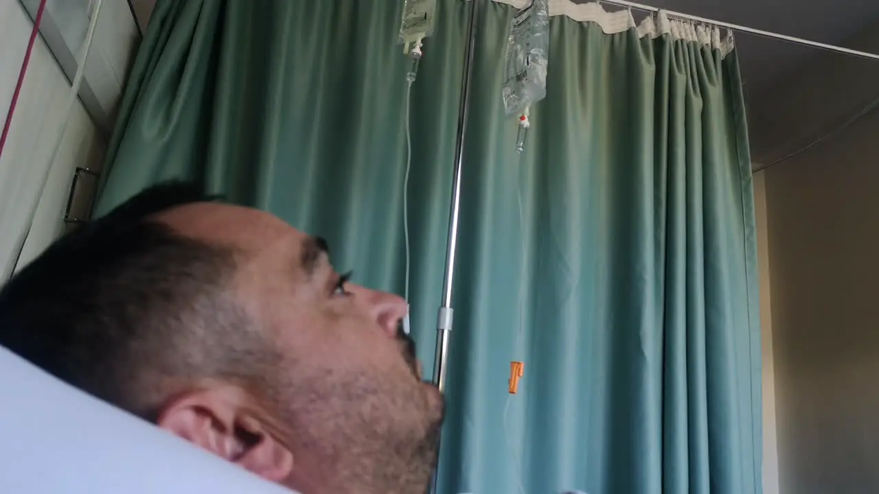 A male patient in the hospital watches his saline drip