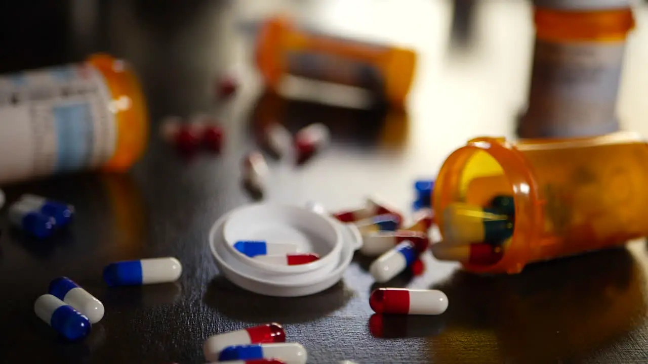 Medicine pills and drugs spilling out of a prescription bottle in slow motion