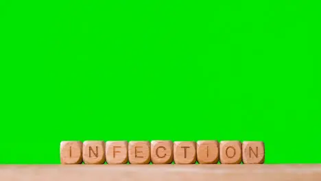 Medical Concept With Wooden Letter Cubes Or Dice Spelling Infection Against Green Screen Background