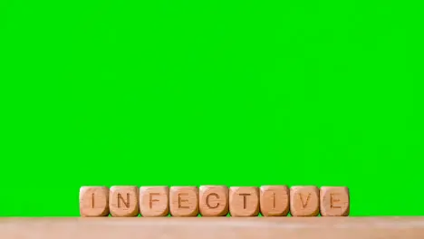 Medical Concept With Wooden Letter Cubes Or Dice Spelling Infective Against Green Screen Background