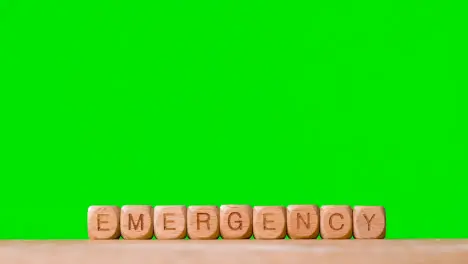 Medical Concept With Wooden Letter Cubes Or Dice Spelling Emergency Against Green Screen Background