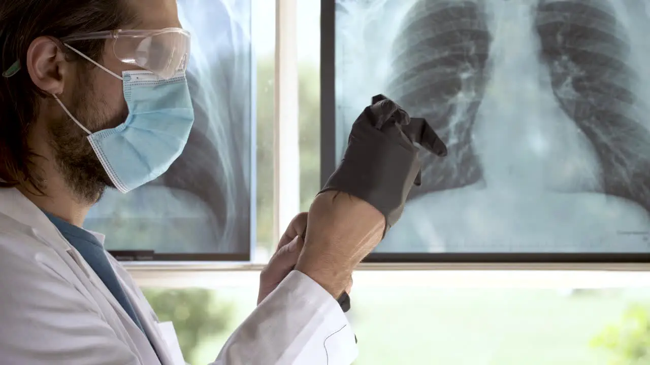 doctor with face mask putting on protective gloves profile view