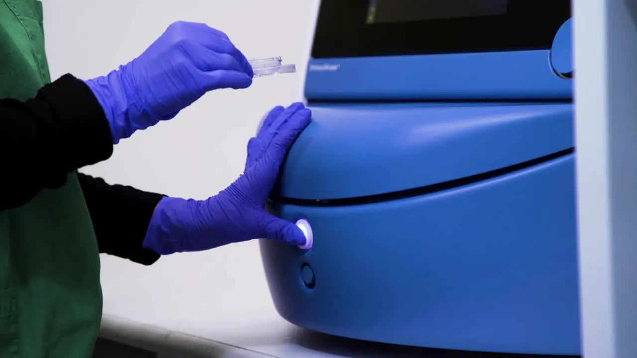 Close up showing a nurse hands opening a machine and putting something inside