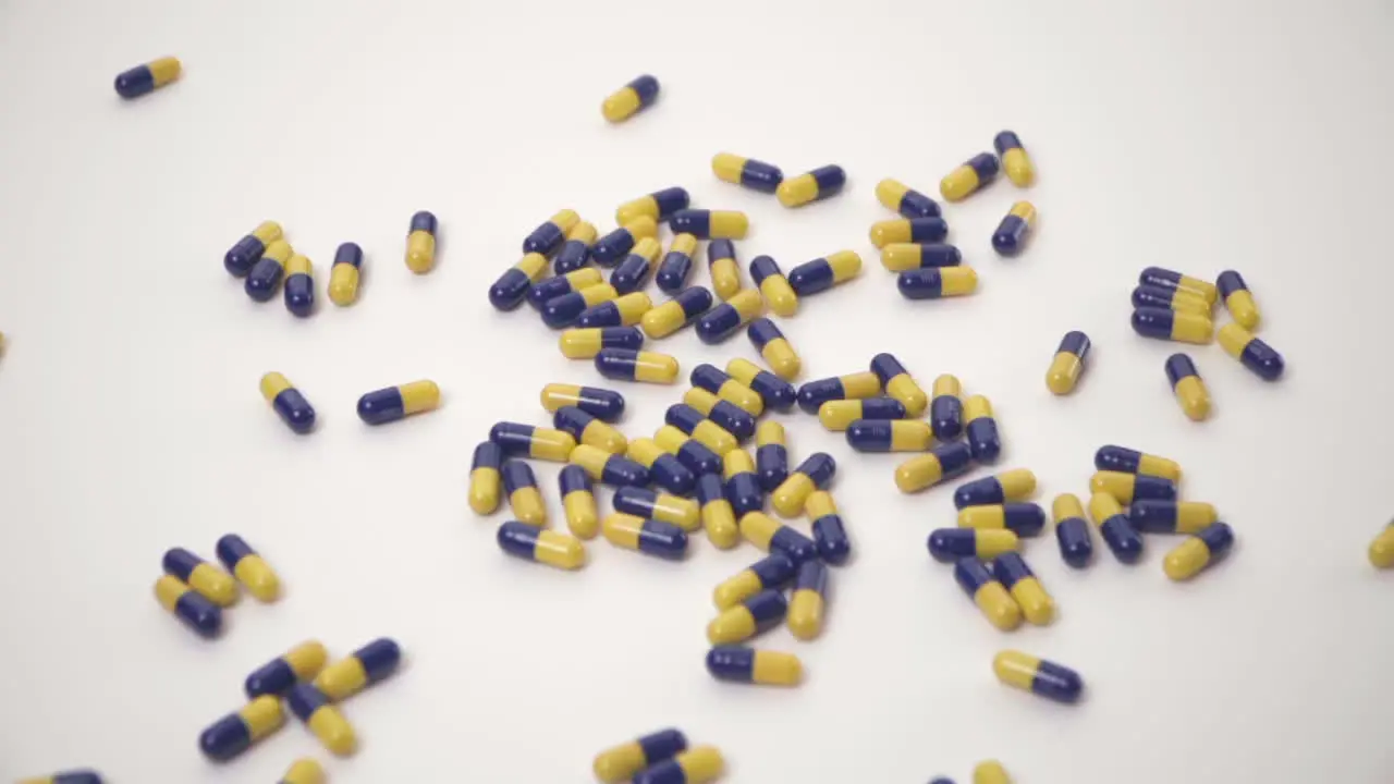 Slow Motion of Blue and Yellow Pills Dropped onto White Background