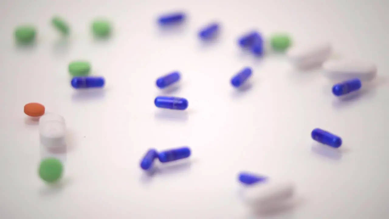 Slow Motion Macro of Pill Varieties Dropped onto White Background