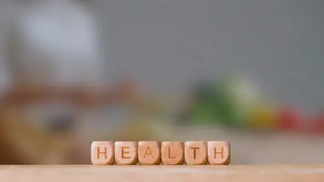 Medical Concept With Wooden Letter Cubes Or Dice Spelling Health Against Background Of Woman Chopping Ingredients