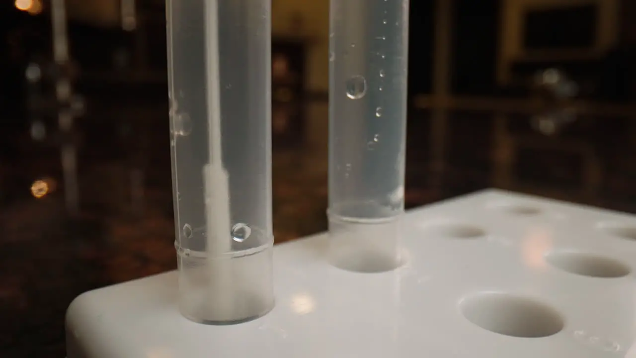 Close-up of a COVID-19 swab being placed into a test tube