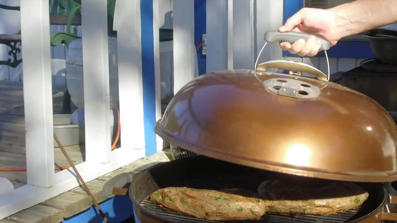 Lifting the lid on a BBQ showing tri-tips cooking