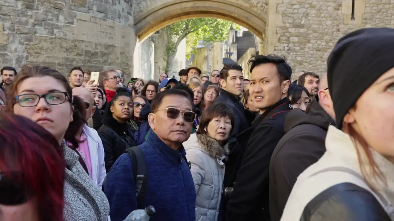 A crowd of different people turn around and look at something in a castle at the same time close up view