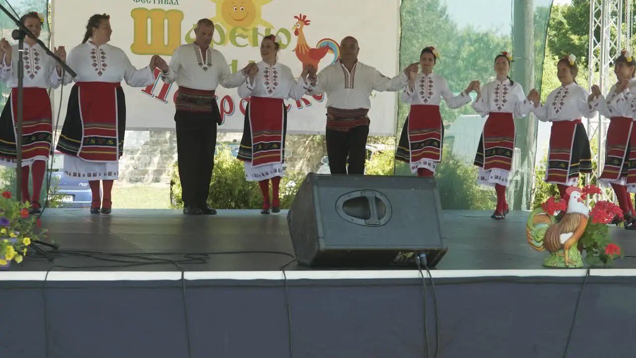 Dance group in traditional costume perform horo on stage at cultural event