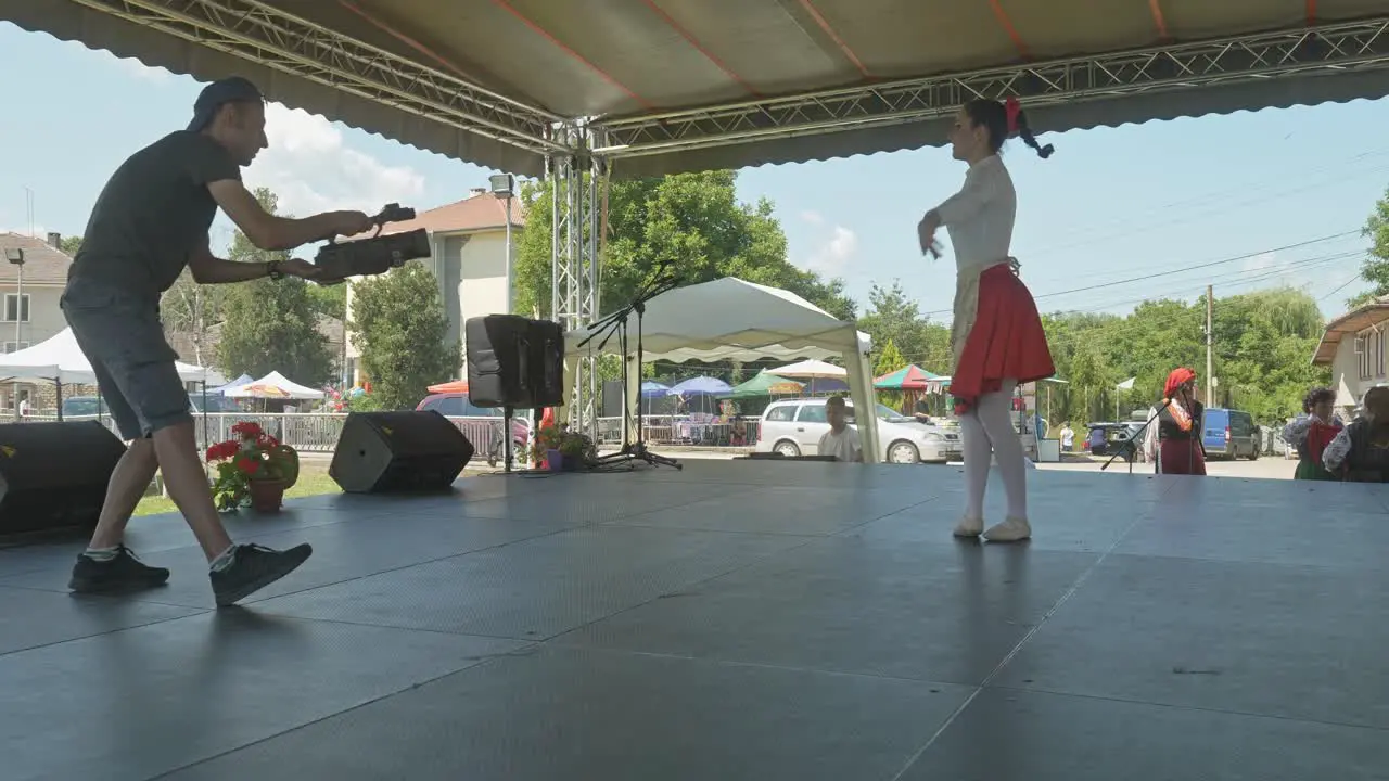 News cameraman films ballet dancer on stage at local cultural festival