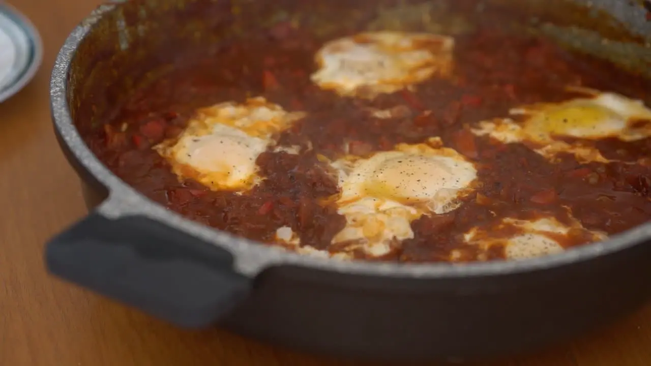 Adding finely ground pepper to homemade shakshuka in slow motion