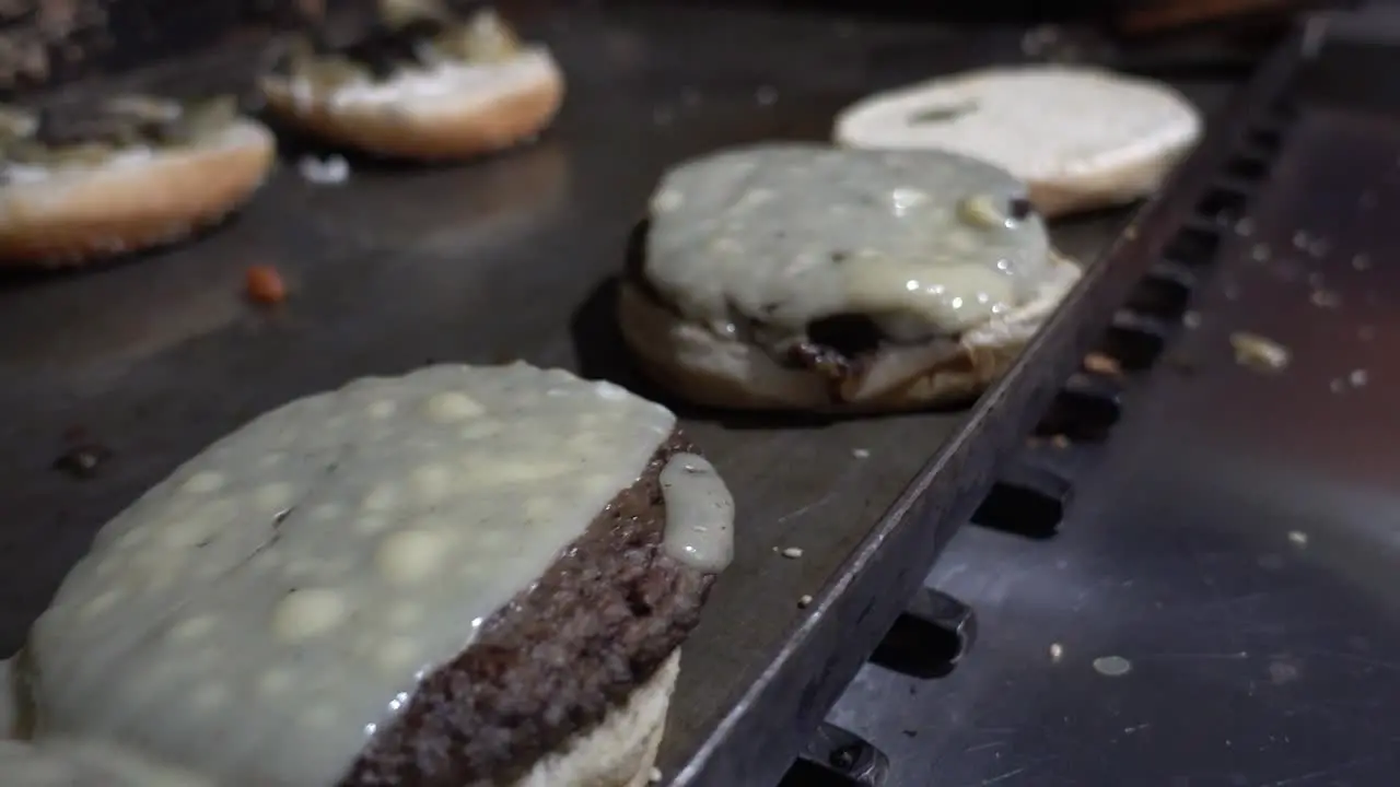 Close-up shot of cheeseburgers cooking on an open-top grill