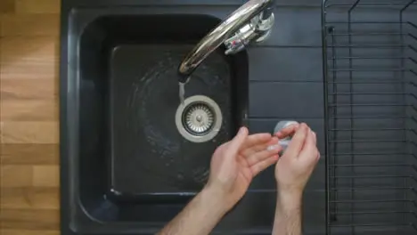 Top Down Shot of Male Hands Turning On Kitchen Tap and Washing with Soap