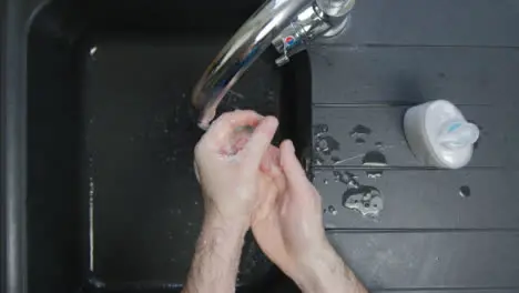 Top Down Shot of Male Hands Washing with Soap Under Running Tap