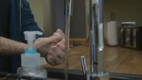 Medium Shot of Male Hands Washing Under Running Water with Soap