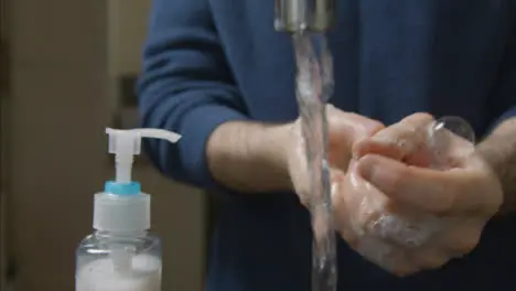 Close Up Shot of Male Hands Washing Under a Running Kitchen Tap with Soap