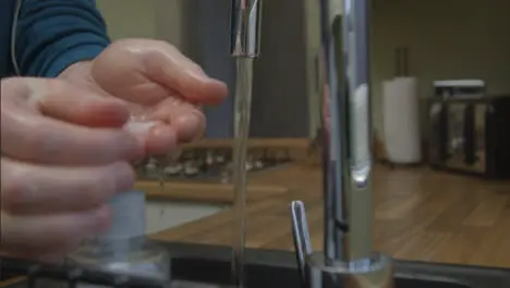 Medium Shot of Male Hands Turning On Kitchen Tap and Washing Under Running Water