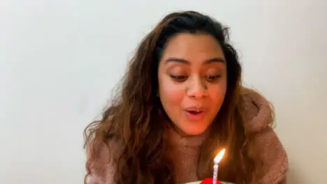 A Young Female Student Blowing Out Candle On Birthday Cake During Video Call