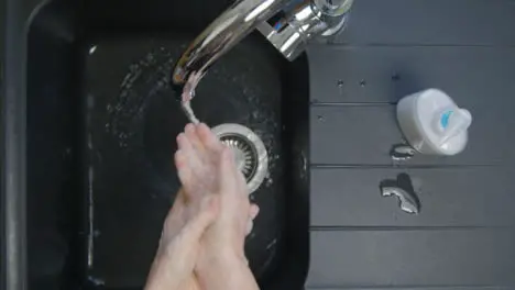 Top Down Shot of Female Hands Rinsing Soap from Hands Under Running Tap