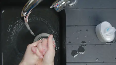 Top Down Shot of Male Hands Turning Washing Underneath Running Tap