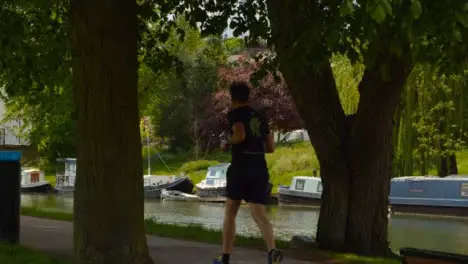 Tracking Shot of Runner On Footpath Next to River Cam