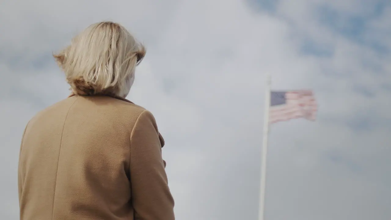 Woman looking at american flag on flagpole rear view