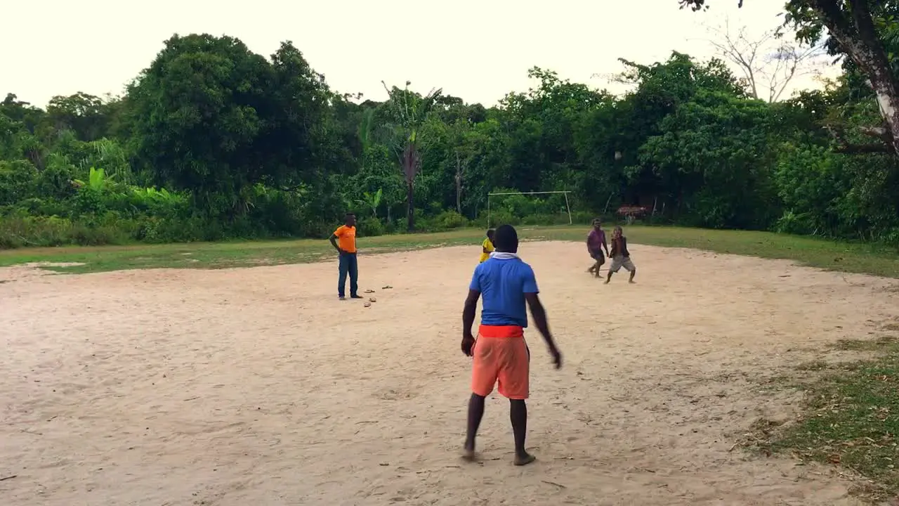 African kids play with the ball on playground in front of forest