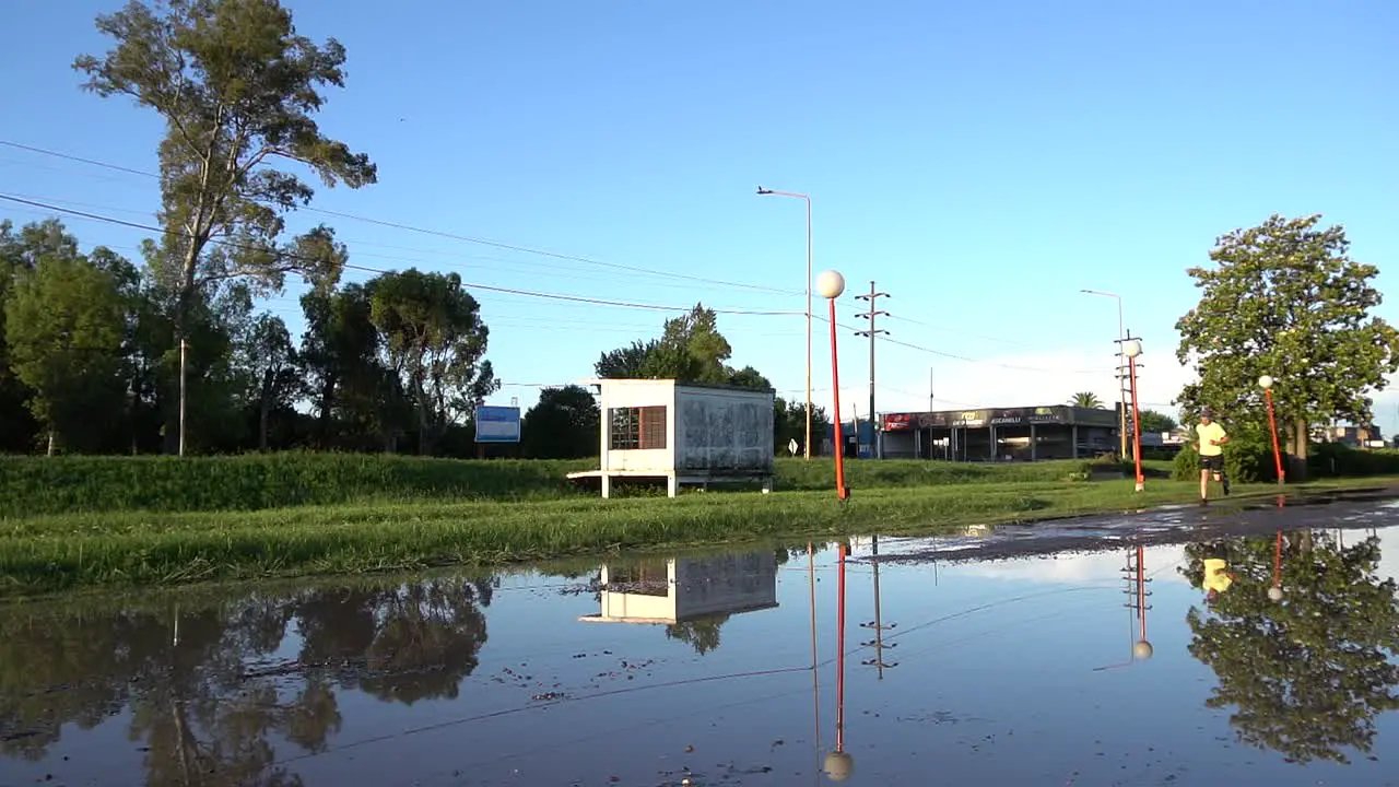 A man runs on a flooded service road on a sunny afternoon