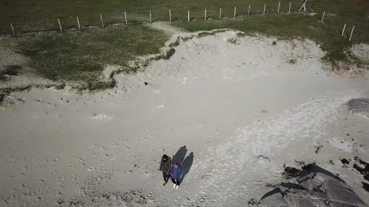 aerial view two people walk on a sandy beach in Connemara Ireland next to fields