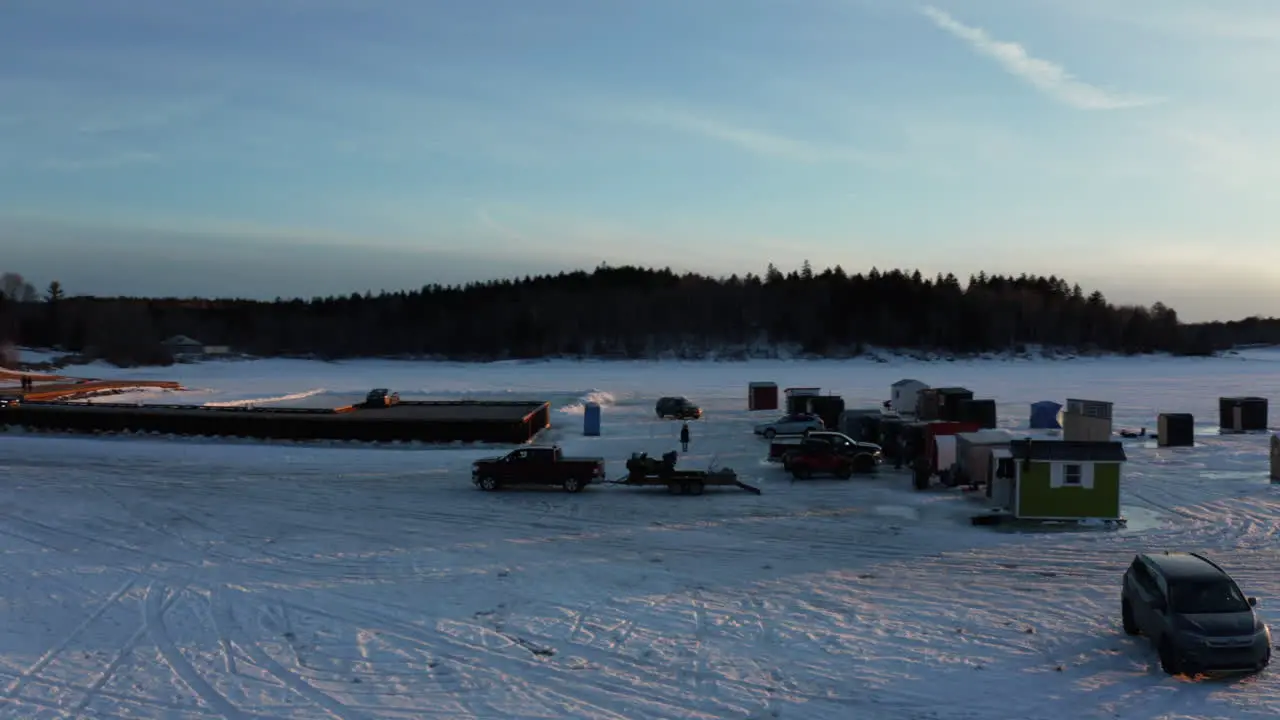 Picturesque aerial view of ice fishing huts on a frozen lake at sunset