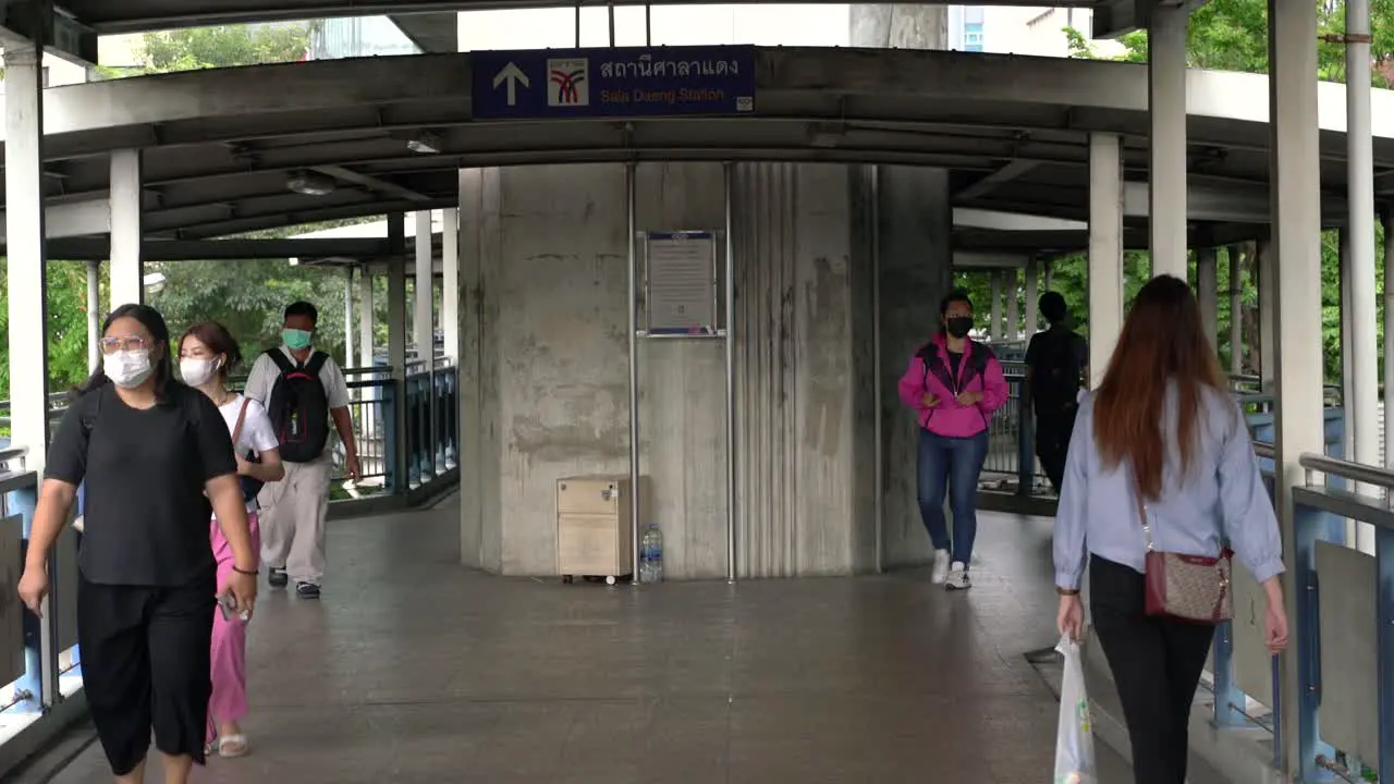 People walking overhead bridge walkway towards SalaDaeng Skytrain station in Bangkok