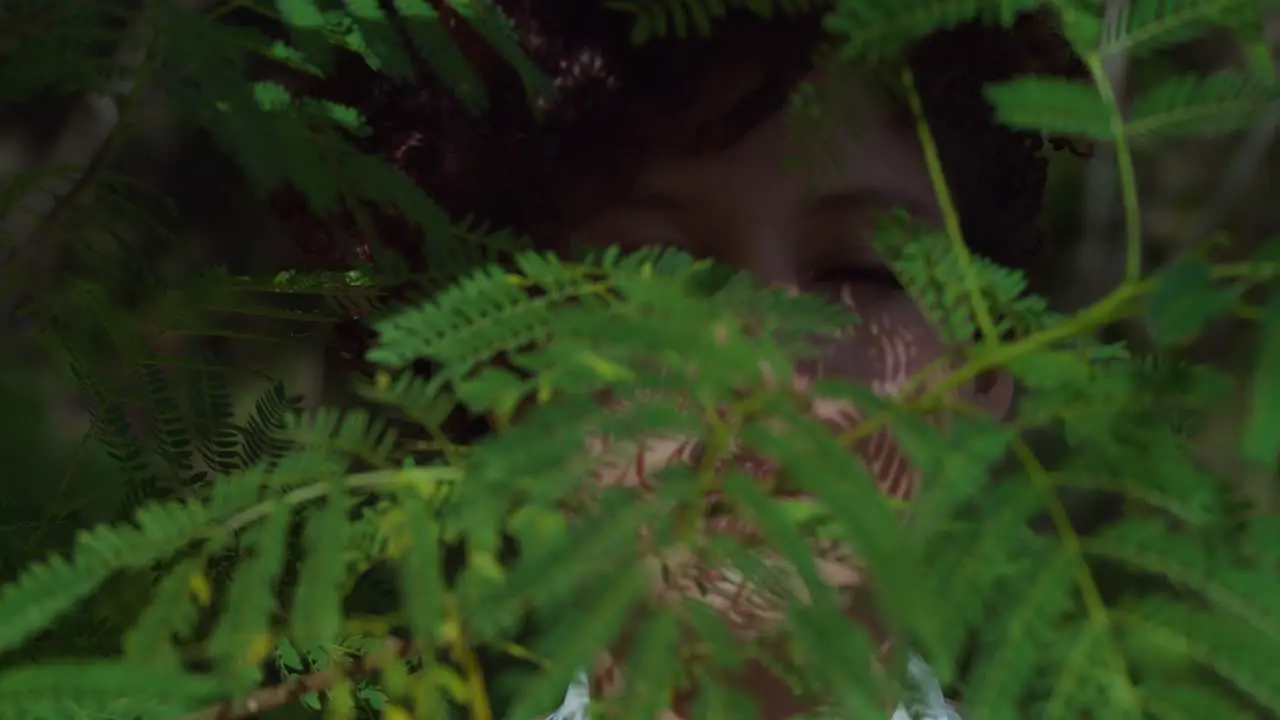 Brown eye latina girl in a park with leaves of a tree in the foreground