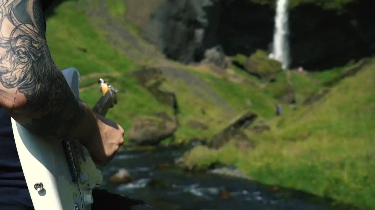 Man playing guitar in front of a beautiful waterfall in Iceland-25