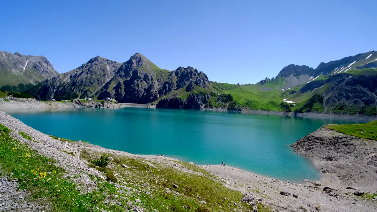 An unrecognizable person by the side of the beautiful lake with the mountain in the background