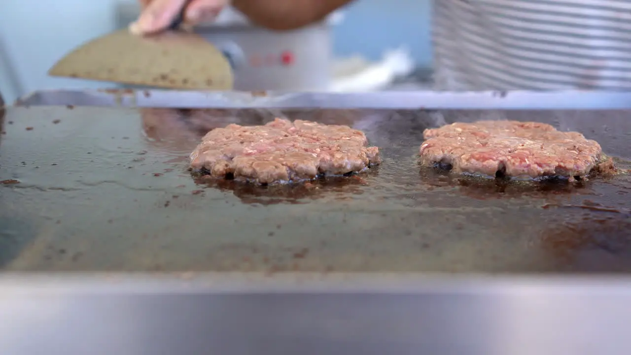 three pieces of Beef burger is cooking on the grill