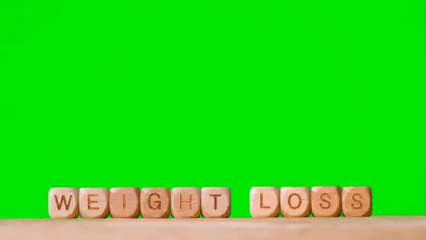 Medical Concept With Wooden Letter Cubes Or Dice Spelling Weight Loss Against Green Screen Background