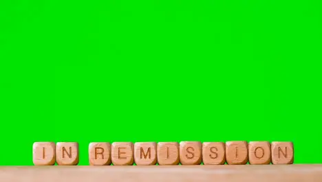 Medical Concept With Wooden Letter Cubes Or Dice Spelling In Remission Against Green Screen Background